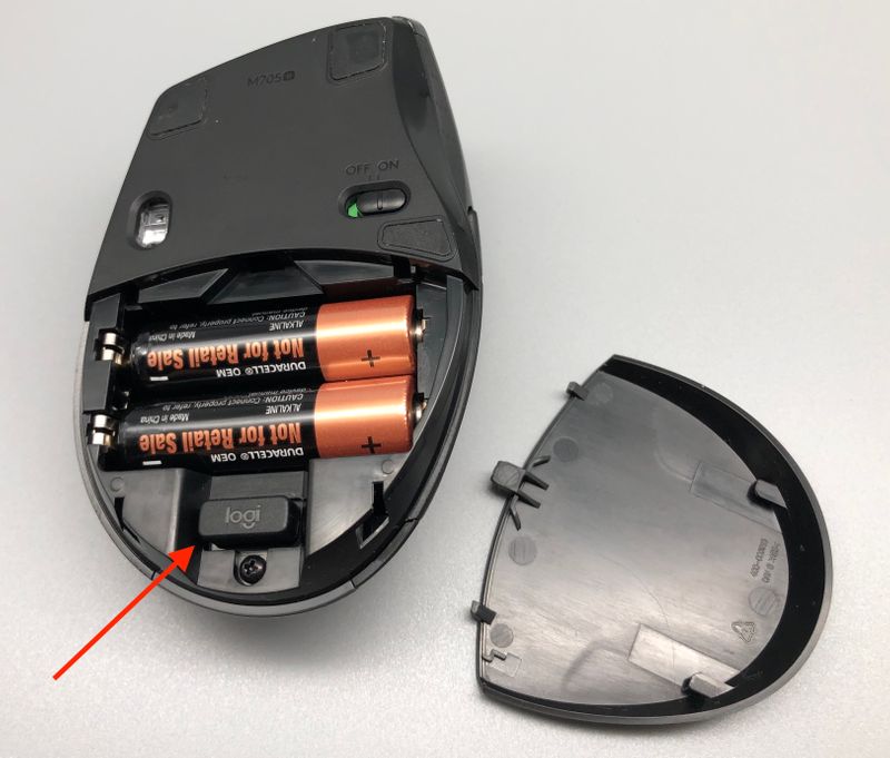 USB Unifying Empfänger in seinem "Transportschacht" (roter Pfeil) und die, im Lieferumfang enthaltenen, AA-Batterien